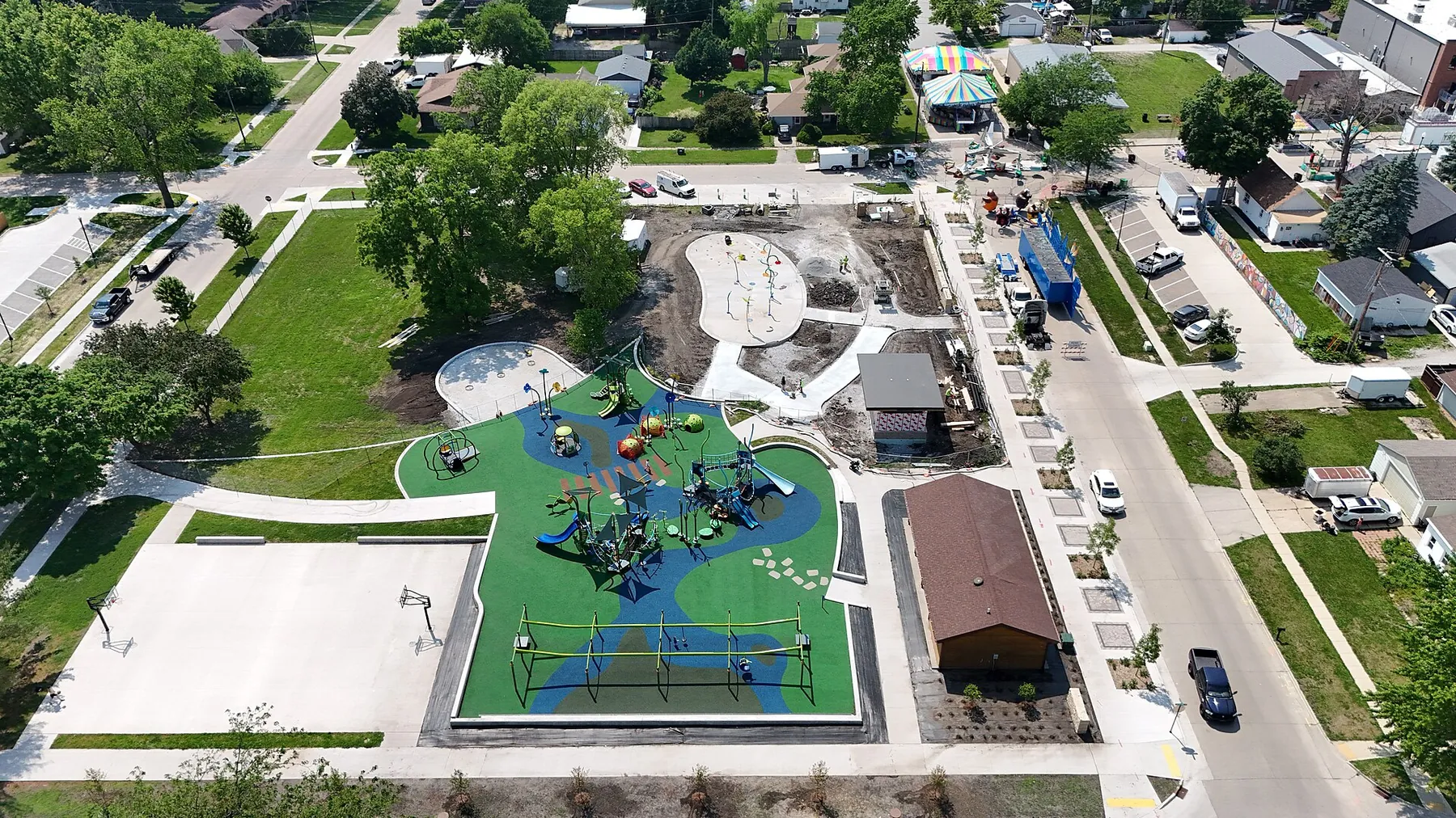 Aerial view of a Bondurant city park with a new playground, lawn and tree-lined residential streets around it