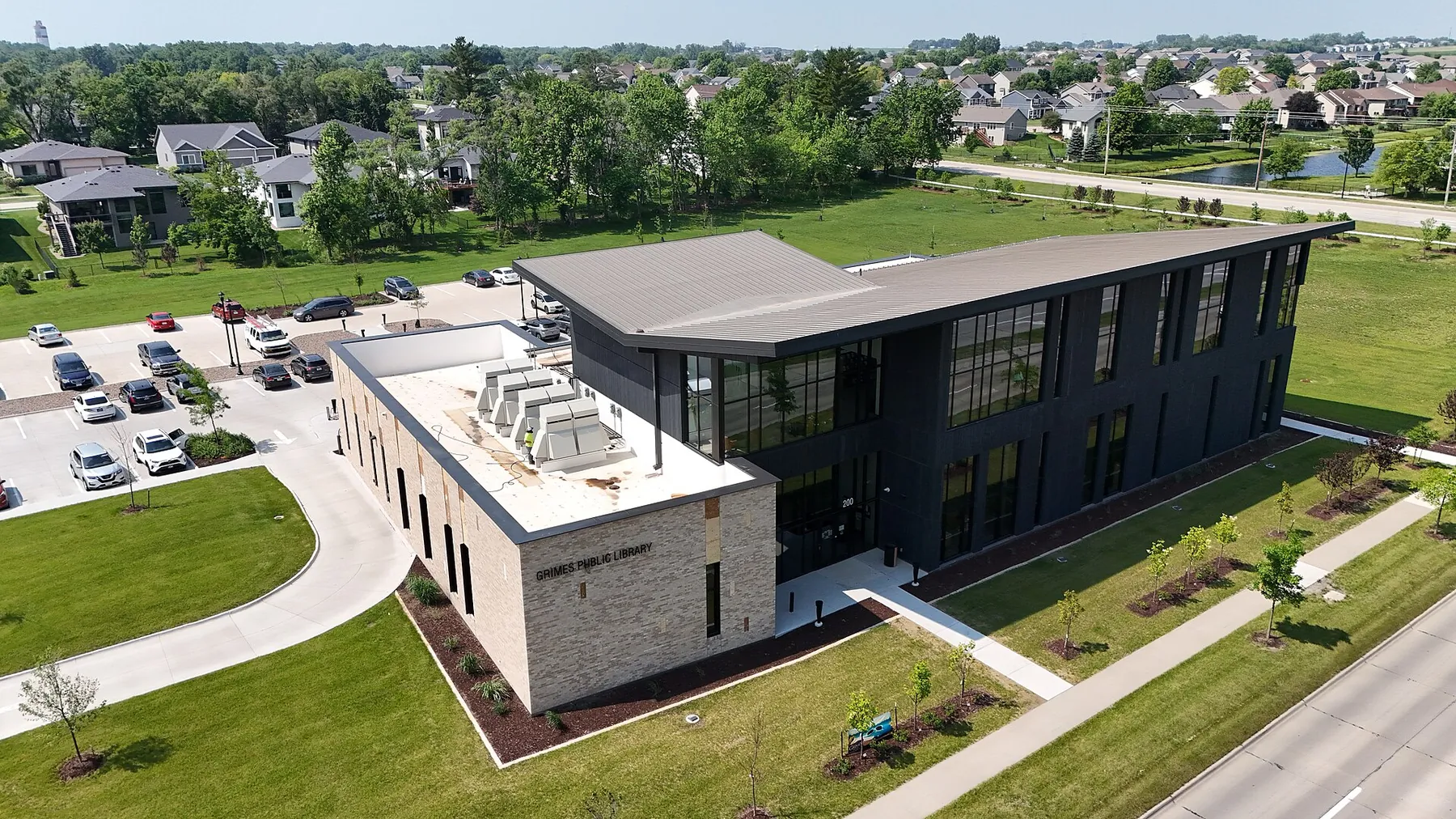 Aerial view of the modern Grimes Public Library with new residential streets and houses stretching behind it